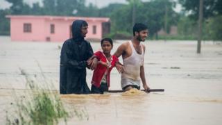 Nepali residents wade along a flood area at Birgunj Parsa district, some 200km south of Kathmandu,