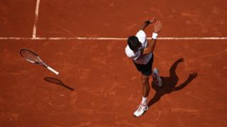 Novak Doković tira la raqueta en el suelo durante un partido