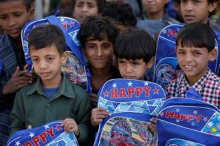 Orphan students carry bags they received from a local charity organisation