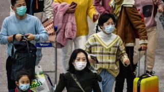 Passengers wearing respiratory masks walk across a terminal on January 31, 2020 in Rome