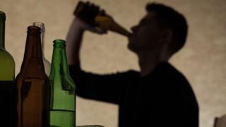Sombra de hombre joven bebiendo alcohol.