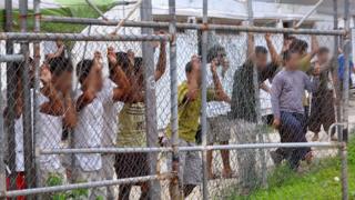 Просители убежища просматривают забор в центре заключения на острове Манус в Папуа-Новой Гвинее