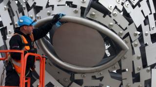 Man inspects eye of Kelpie