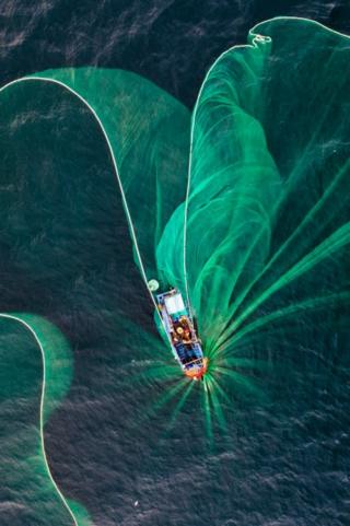 This strange looking image is called the The Fishing Net and was taken by photographer Trung Pham Huy who added: "The fishing net during anchovy fishing season looks like a floating flower on the sea in this aerial view."