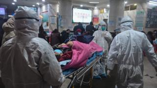 Medical staff carry a patient into a Wuhan Red Cross hospital