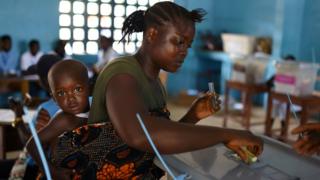 A voter casts her ballot at a polling station during Sierra Leone"s general election in Freetown, Sierra Leone March 7, 2018.