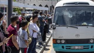 Residents queue for a bus after the Jordanian government started to ease the lockdown, 10 May 2020