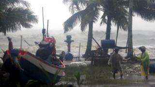 Thai villagers evacuate as high waves are seen in the background