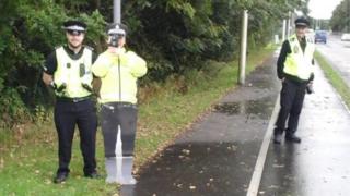 Police officers standing beside cutout officer