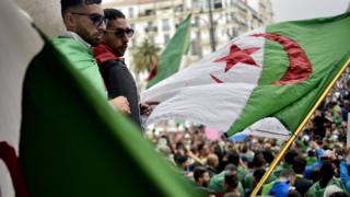 Algerian protesters wave a national flag as they take part in a demonstration in the capital Algiers on May 3, 2019. - Algerians gathered for an 11th consecutive Friday of demonstrations.
