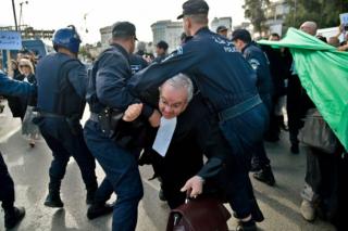 An Algerian lawyer tries to break through the police line during a protest against ailing president's bid for a fifth term in power, in Algiers on 7 March 2019.