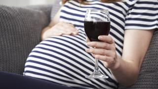Беременная женщина пьет вино