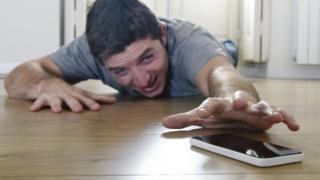 Hombre intentando alcanzar su celular