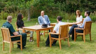 The Duke and Duchess sitting around a table outside in a socially distanced way