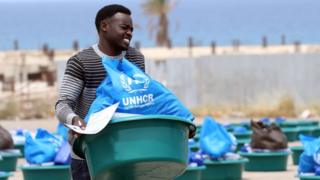 A man caries a bowl with aid items at a United Nations' High Commissioner for Refugees (UNHCR) camp for displaced Libyans and asylum seekers, on May 12, 2020 in the Libyan capital Tripoli during the Muslim holy month of Ramadan.