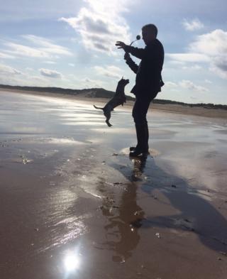 Silhouette of a man with a dog on a beach