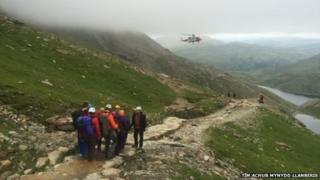 Aelodau o Dîm Achub Mynydd Llanberis yn cludo claf at hofrennydd