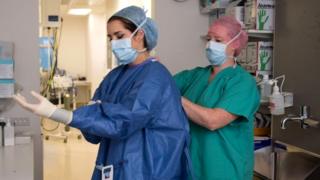 A surgical care practitioner prepares to enter an operating theatre.