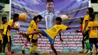 Un grupo de niños juega rente a un retrato de Messi