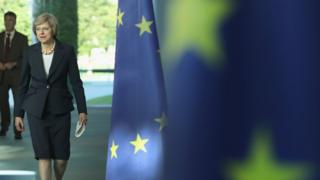 British Prime Minister Theresa May walks past European Union flags as she and German Chancellor Angela Merkel (not pictured) arrive to speak to the media following talks at the Chancellery on July 20, 2016 in Berlin, Germany.