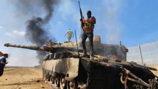 Person holding gun standing on a tank