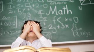Criança com as mãos tampando o rosto na sala de aula