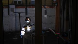 Cleaner wears a mask as washes windows