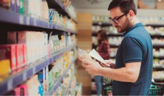 Homem olha rótulos de produtos em supermercado