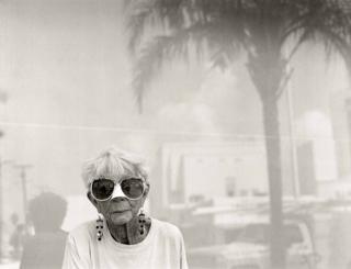 An elderly woman with big sunglasses looks to the camera