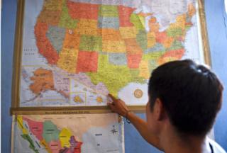 Migrante señala mapa de EE.UU., bajo la cual tiene una de México.