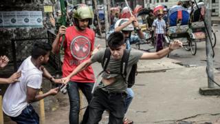 ৫ই অগাস্ট ঢাকার জিগাতলায় দুজন পেটাচ্ছে এবং একজন এই ফটোসাংবাদিকের কাছ থেকে ক্যামেরা ছিনিয়ে নেয়ার চেষ্টা করছে।