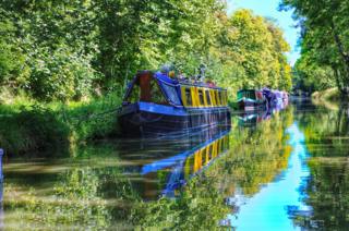 Canal boats reflected in the river