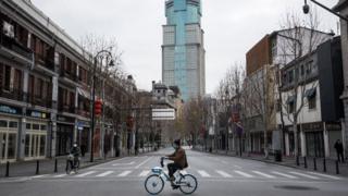 A man by bicycles past an empty street on February 8, 2020 in Wuhan, Hubei province, China.