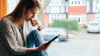 Woman sits in front of window on phone