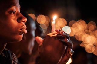 A person holds a candle during a night vigil and prayer at the Amahoro Stadium in Kigali