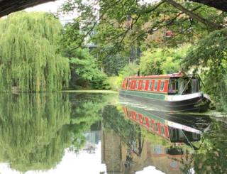 A canal boat reflected in water