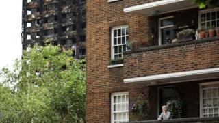 Woman on balcony next to Grenfell Tower