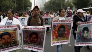 Relatives hold pictures of some of the 43 missing students of Ayotzinapa College Raul Isidro Burgos during a march in Mexico City.