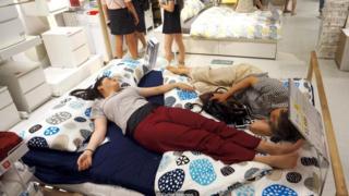 Người ta ngủ trưa trên giường tại một cửa hàng Ikea để tránh cái nóng bên ngoài ở Hàng Châu, Trung Quốc, năm 2017.