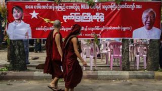 Monks pass in front of an NLD banner celebrating Myanmar's new President Htin Kyaw