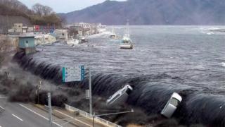 Tsunami breeching an embankment and flowing into the city of Miyako in 2011