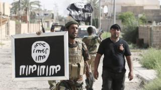 Iraqi Shia militiamen hold an Islamic State flag upside down after capturing the town of Saqlawiya, north of Falluja, on 4 June 2016