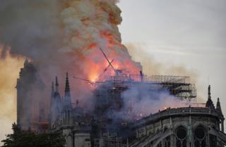 The spire collapses while flames are burning the roof of the Notre-Dame Cathedral