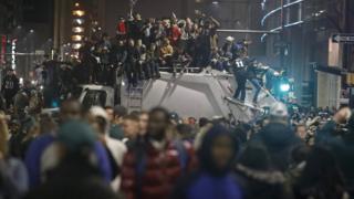 People sit on a broken traffic light while celebrating the Philadelphia Eagles' victory in Super Bowl LII game against the New England Patriots on 5 February 2018 in Philadelphia, Pennsylvania.