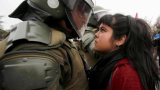 Una joven se enfrenta a un policía en una protesta