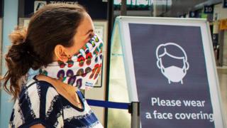 Mujer en la estación de ferrocarril con una máscara facial