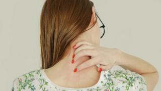 A woman trying to scratch the back of her neck