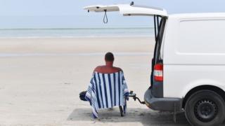 Man sits in the shade on a beach in Adelaide, Australia