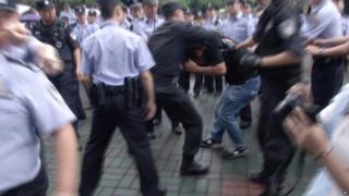 Police scuffle with a protestor outside the municipal government headquarters in Shanghai (27 June 2015)