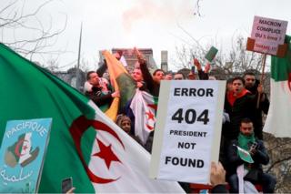 Protesters hold up flags and placards, one of which reads "Error 404 president not found" on 7 March 2019.